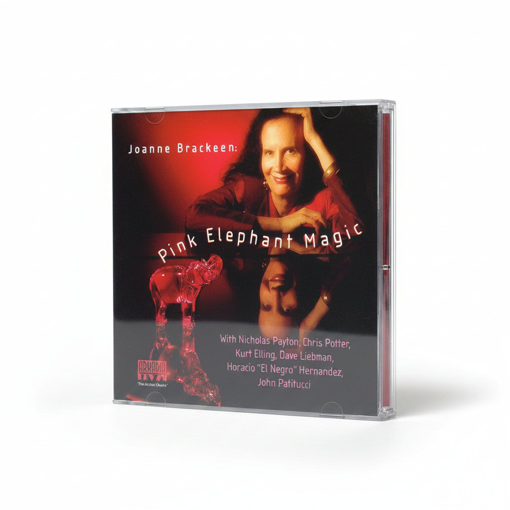 A CD case for Joanne Brackeen's 'Pink Elephant Magic' standing upright on a light gray background. The cover features a portrait of Joanne Brackeen, a red elephant figurine, and the title in white text.